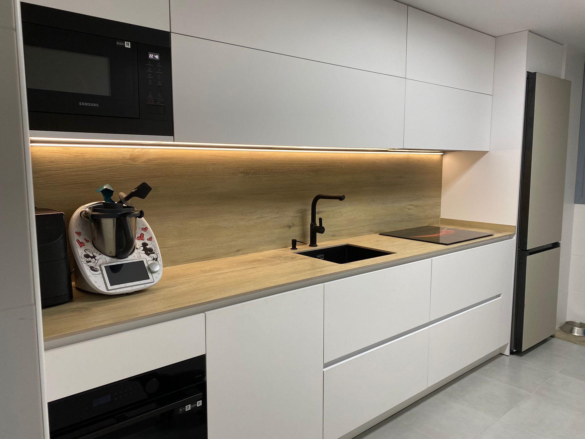 Cocina blanca con encimera de roble y luz LED