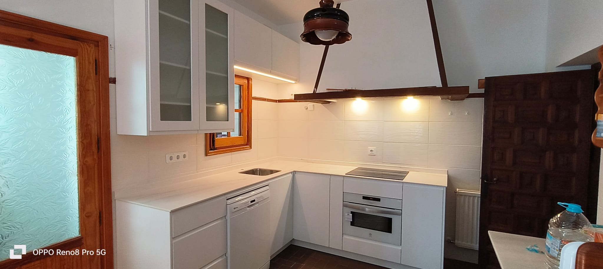 Cocina blanca en casa rústica con vigas de madera