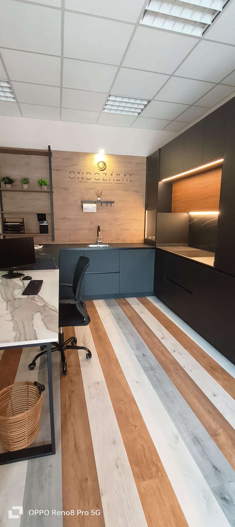 Zona de exposición con mobiliario oscuro y suelos de madera